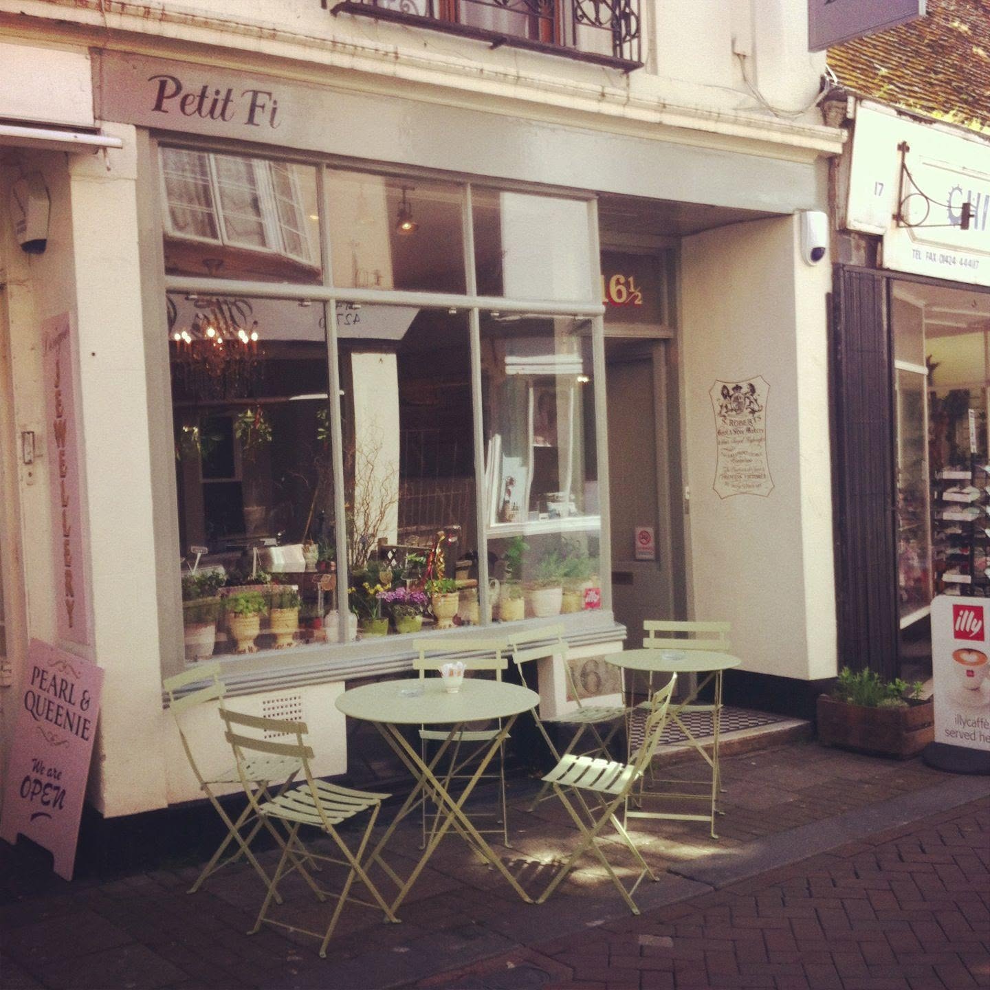Historic Petit Fi frontage with its complete shop sign, entrance and pale green pavement tables